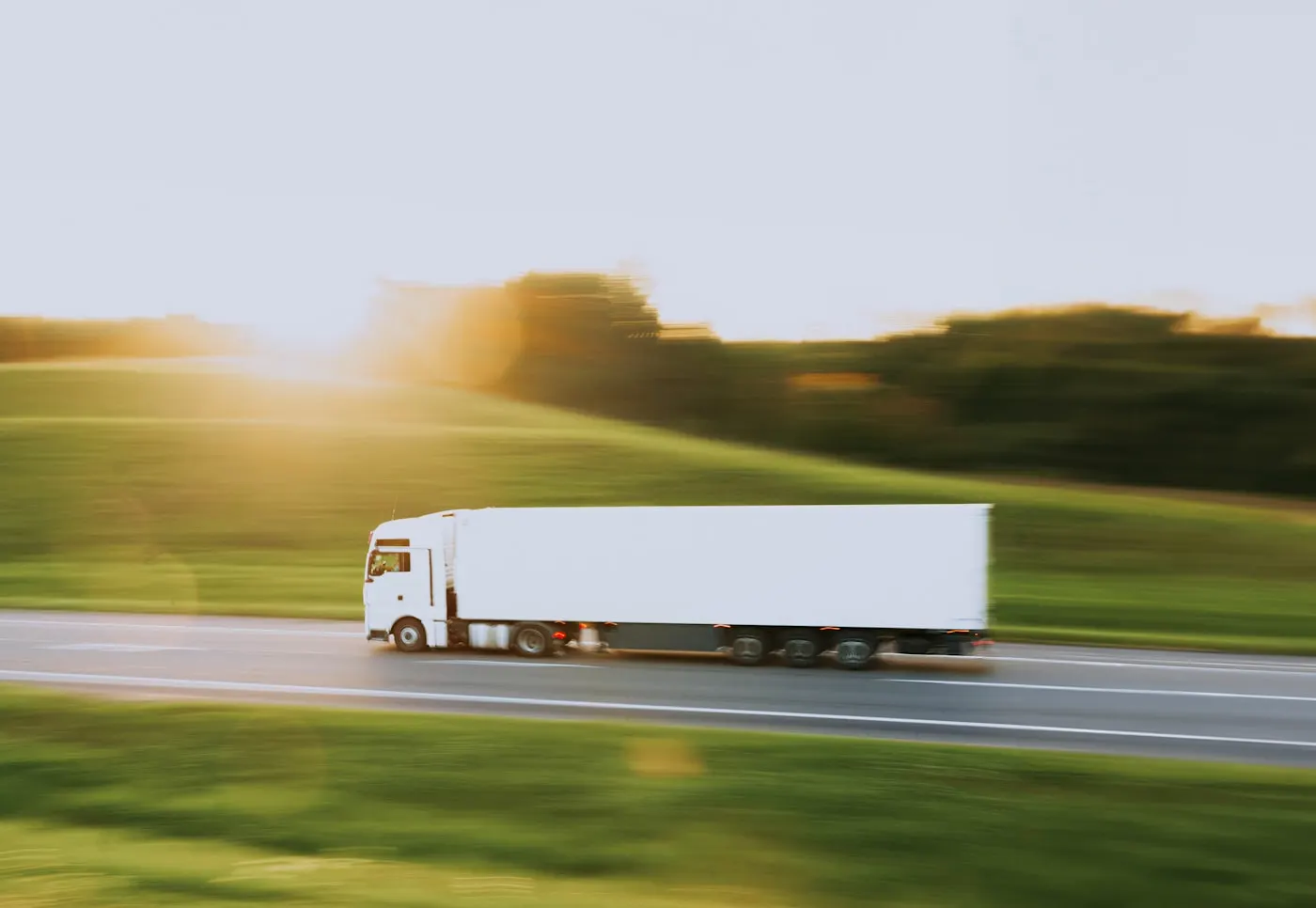 A freight truck traveling down a highway past open fields