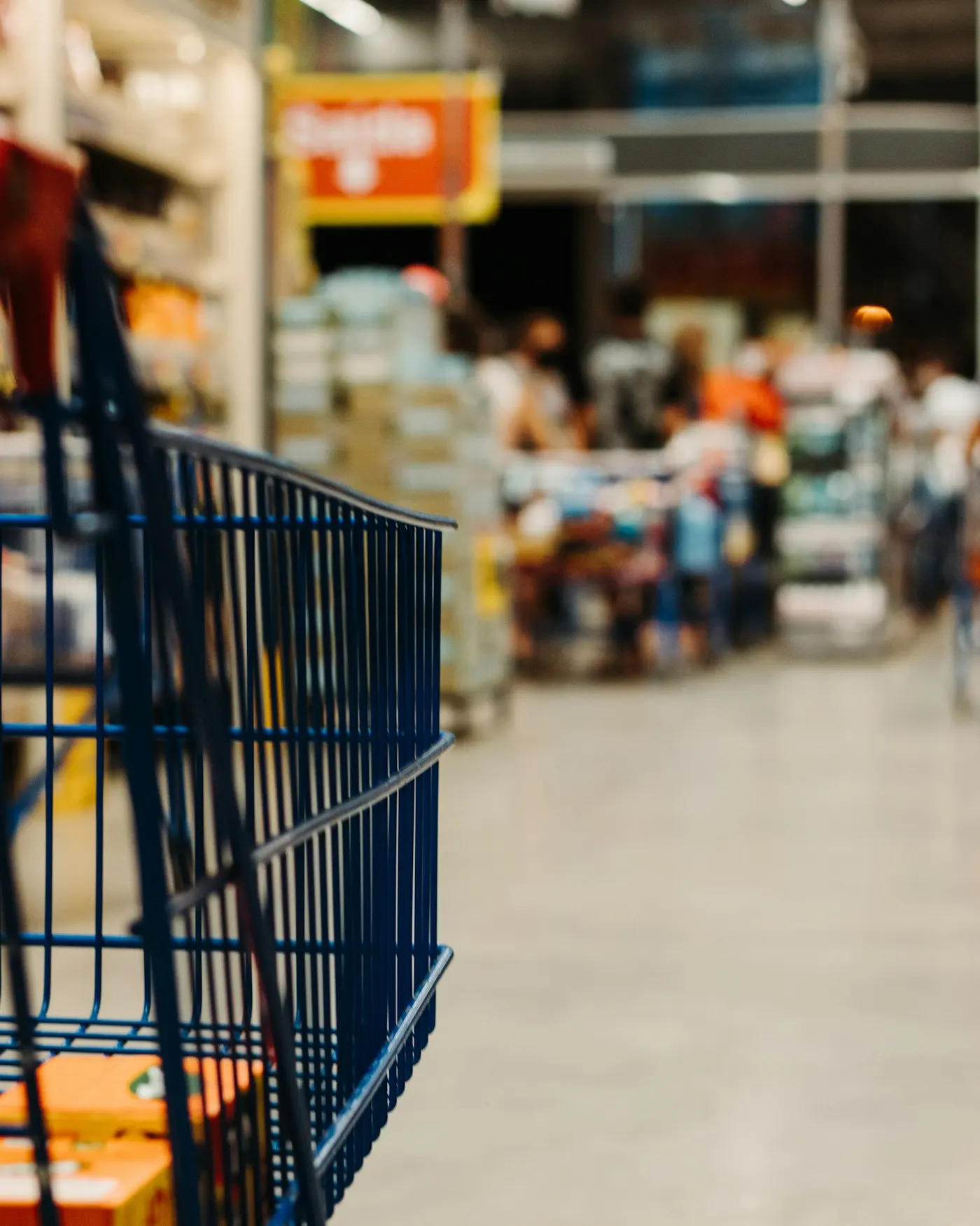 A shopping cart pushed down a stocked store aisle