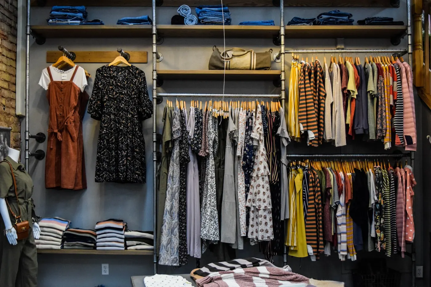 A shop wall of open shelving stocked with folded goods and bags